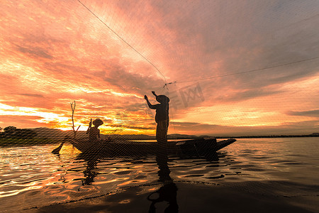 泰国早上在船上用网捕鱼的轮廓渔夫、自然与文化概念