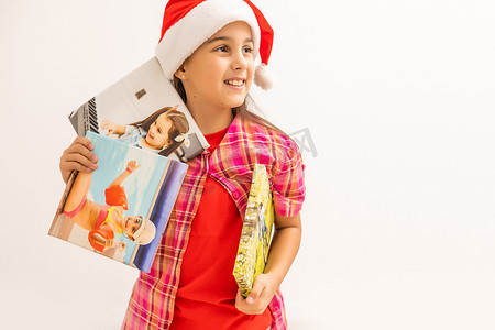 戴着圣诞老人帽子的小女孩微笑着，手里拿着照片画布。