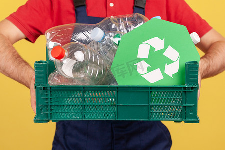 未知摄影照片_未知工人拿着装有塑料瓶的盒子和绿色回收标志，生态问题。