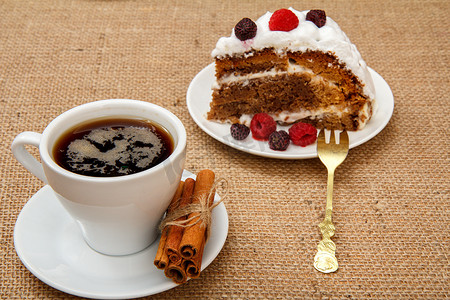 霜果实摄影照片_一杯咖啡、肉桂、叉子和一片饼干蛋糕，配覆盆子