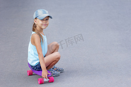 微笑的孩子坐在路上的滑板上