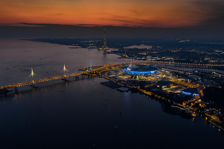 足球足球日摄影照片_俄罗斯，圣彼得堡，2022年8月17日：风景如画的日落，俄罗斯天然气工业股份公司竞技场足球场，欧洲最高的摩天大楼拉赫塔和一座斜拉桥，照明高速公路