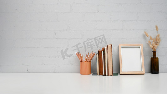 家庭办公桌，白色桌子上有空白相框、书籍和笔架。