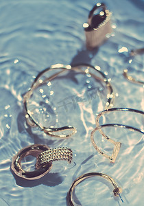 金手镯、耳环、戒指、蓝色水背景珠宝、奢华魅力和珠宝品牌广告的假日美容设计