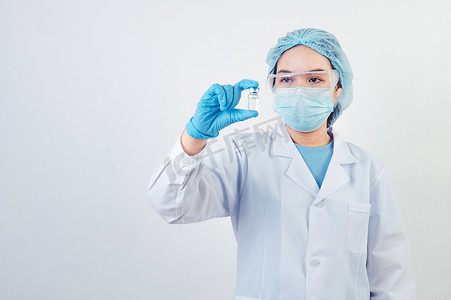 专业科学家或医生在实验室手持 Covid-19 疫苗瓶，用白色背景的面罩手套和实验室外套进行治疗。