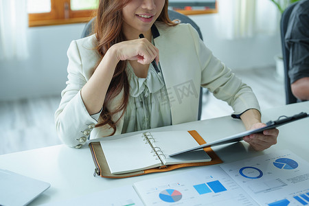 一位女商人拿着预算文件，并使用放在桌上的计算机和计算器来分析投资以管理其企业风险的肖像