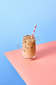 上高铁摄影照片_粉红色桌子和蓝色背景上高杯中的冰咖啡和牛奶。