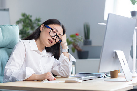 一位悲伤的亚洲女商人对自己的能力感到绝望，心情沮丧，在办公室的电脑前工作