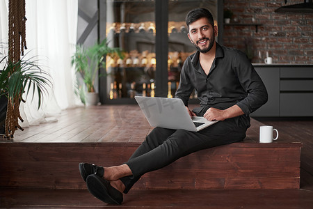 新企业主坐在地板上使用笔记本电脑。