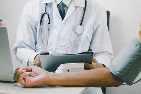 医生测量一位老年男性患者的血压。