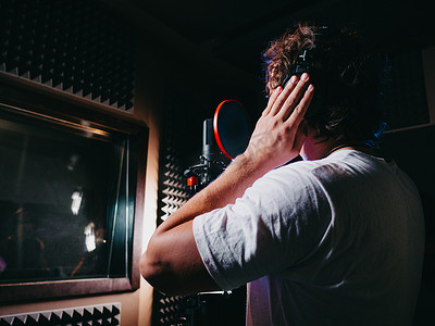 歌手摄影照片_年轻英俊的歌手在录音室戴上耳机。