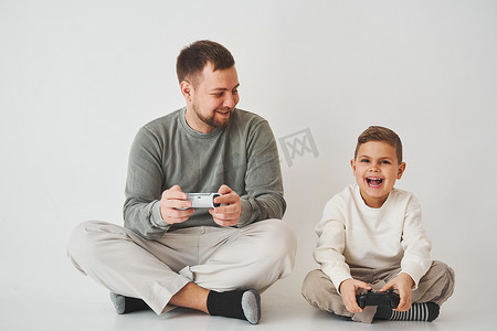 儿子和爸爸用游戏手柄玩游戏机游戏。