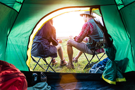 男女露营者在露营帐篷前互相交谈。