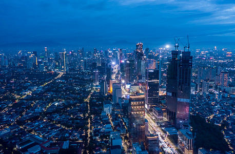 2021年，印度尼西亚雅加达夜间高楼林立的现代城市景观空中全景，蓝色夜光下的摩天大楼和住宅区