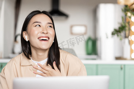 哈哈大笑卡通人物摄影照片_快乐的亚洲女人在家用电脑放松、大笑、在笔记本电脑上观看视频