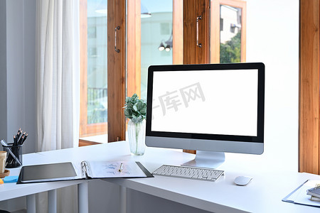 数字化办公摄影照片_现代工作区，白色桌子上配有计算机、办公用品和室内植物。
