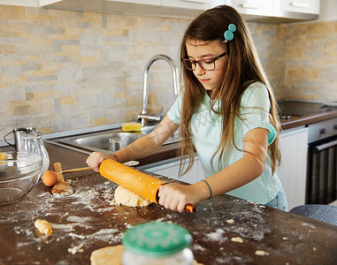 围裙摄影照片_儿童女孩厨房烹饪食品面粉面团准备配料烘焙自制糕点鸡蛋厨师童年家庭烘焙围裙蛋糕制作