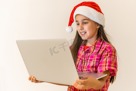 有圣诞老人帽子和膝上型计算机的快乐的小孩