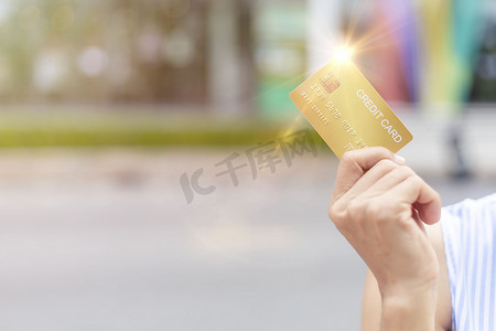妇女手持金信用卡会员卡在模糊的百货商店背景。