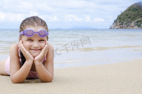快乐的小女孩躺在沙滩上的学龄前儿童