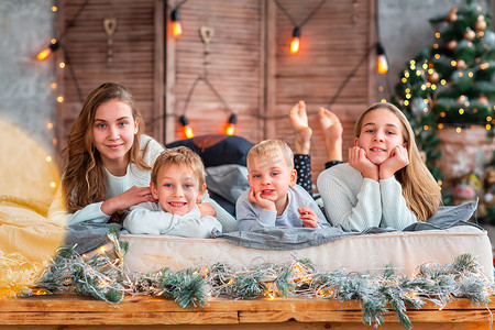 圣诞节早上，快乐的孩子们在圣诞树附近的床上玩得很开心