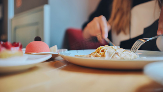 一桌点心摄影照片_女孩早餐时的一桌蛋糕和咖啡。