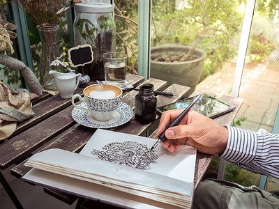 男性手绘涂鸦线条艺术在纸上与咖啡和桌子