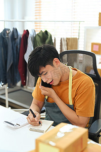 微笑的亚洲男子通过手机确认顾客的订单。