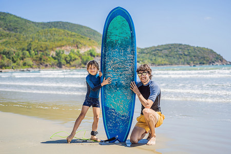 父亲或教练教他的儿子如何在假期或假期在海上冲浪。