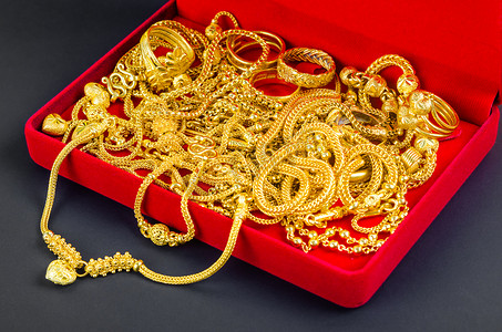 许多金项链在红色天鹅绒盒子里，红色背景。
