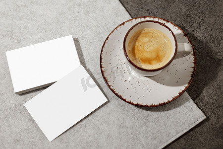 一杯咖啡摄影照片_桌子上的空白白色名片，还有一杯咖啡。