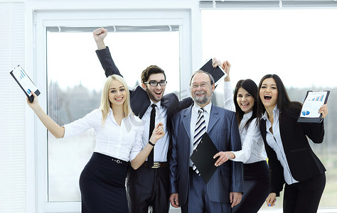 快乐的商业团队举手，欢欣鼓舞。成功的概念