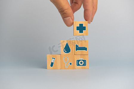 平面图符号摄影照片_手持木制立方体块，背景和复制空间上带有保险保健汽车医疗符号。