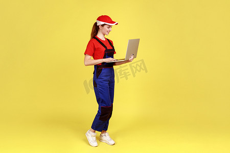 订单处理摄影照片_微笑的女工在笔记本电脑上工作，处理在线订单，表达积极的情绪。