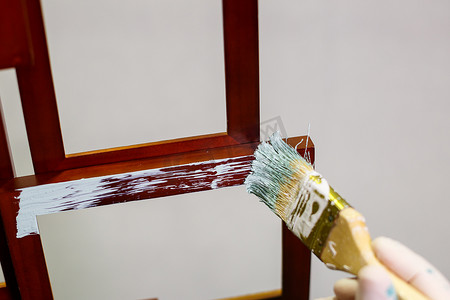 大师用刷子在木制棕色相框上涂上浅色油漆