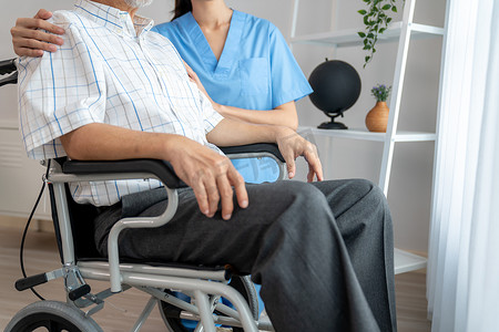 爱心盒饭摄影照片_充满爱心的护士和一位坐在轮椅上的心满意足的老人在家。