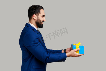 买送摄影照片_积极的男人送蓝色包装的礼物盒，祝贺节日，拿着礼物。