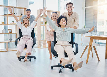 快乐的商务人士在工作时用椅子玩办公室游戏，庆祝初创公司的成功和自由，以及工作中疯狂的团队合作。