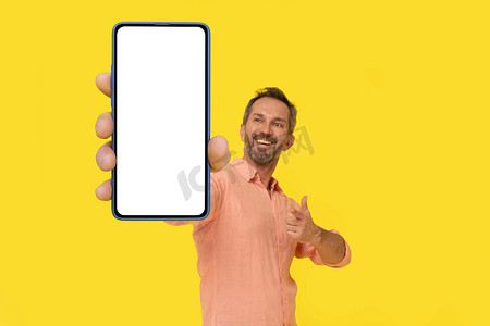 中年灰发男子指着手中的智能手机，惊讶地微笑着看着穿着黄色隔离桃色衬衫的智能手机。