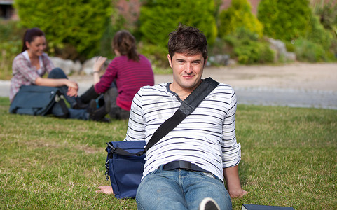 帅气男学生背着书包躺在草地上