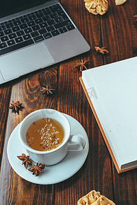 茶手写摄影照片_木桌上的笔记本电脑、茶和笔记本