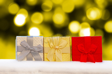 雪地上的彩色 Gif 盒子礼物，背景是金色的圣诞灯