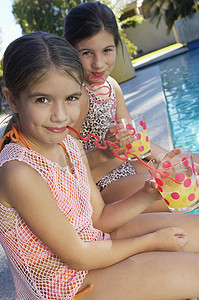 泳池边可爱姐妹们用疯狂吸管喝果汁的肖像