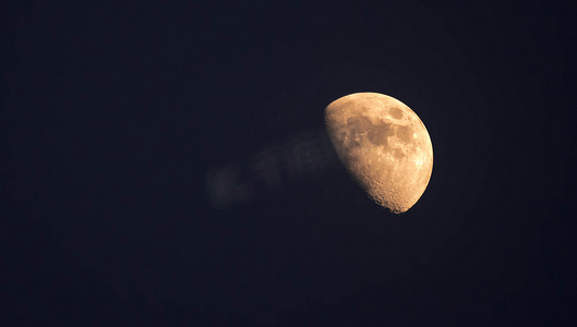 夜间晴朗天空中看到的黄色半月的极端变焦远摄照片
