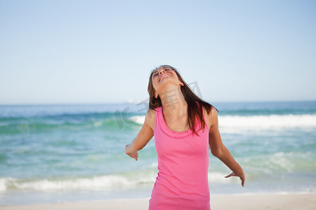 年轻微笑的女人站在海滩上享受阳光