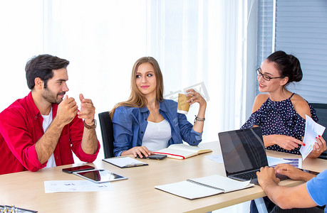 在办公室用台式电脑工作的商务人士，一群穿着商务休闲装的快乐商务人士看着笔记本电脑并打手势。