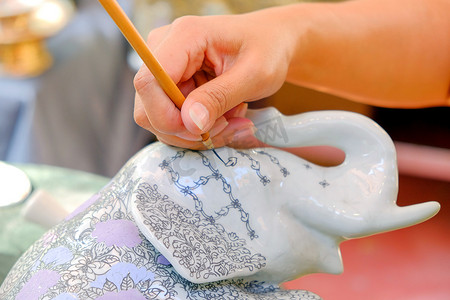 手工艺人正在用画笔在大象雕像上绘制图案