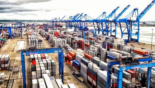 信使摄影照片_日出造船厂带工作起重机桥的集装箱货船和货机的物流运输、物流进出口和运输行业背景