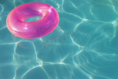 游泳池水面上漂浮的粉色充气管