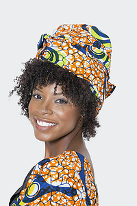 身穿非洲印花服装的年轻女子在灰色背景下回头看的肖像